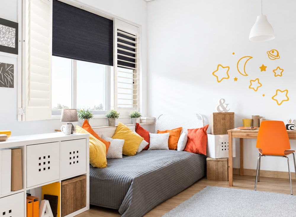 Bright bedroom with white shutters folded open and a dark room darkening blind lowered behind them