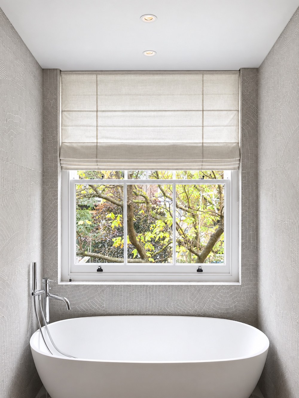 Natural linen Roman blind above a sash window behind a freestanding bath