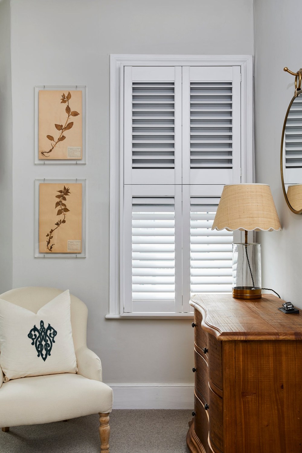 Integrated room-darkening blind fitted behind white plantation shutters in a bedroom