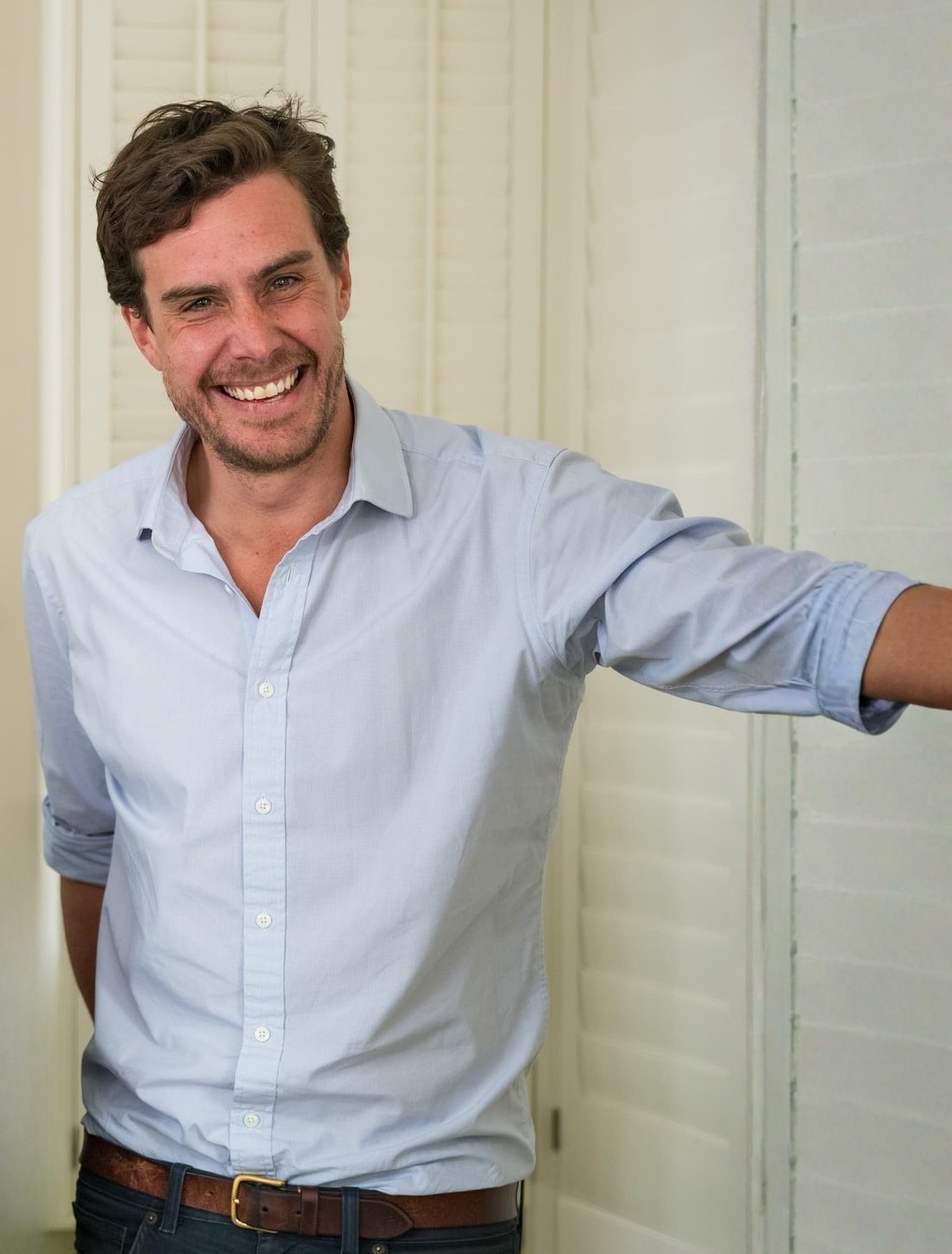 Ben, owner of The Shutter Shop, smiling beside white plantation shutters