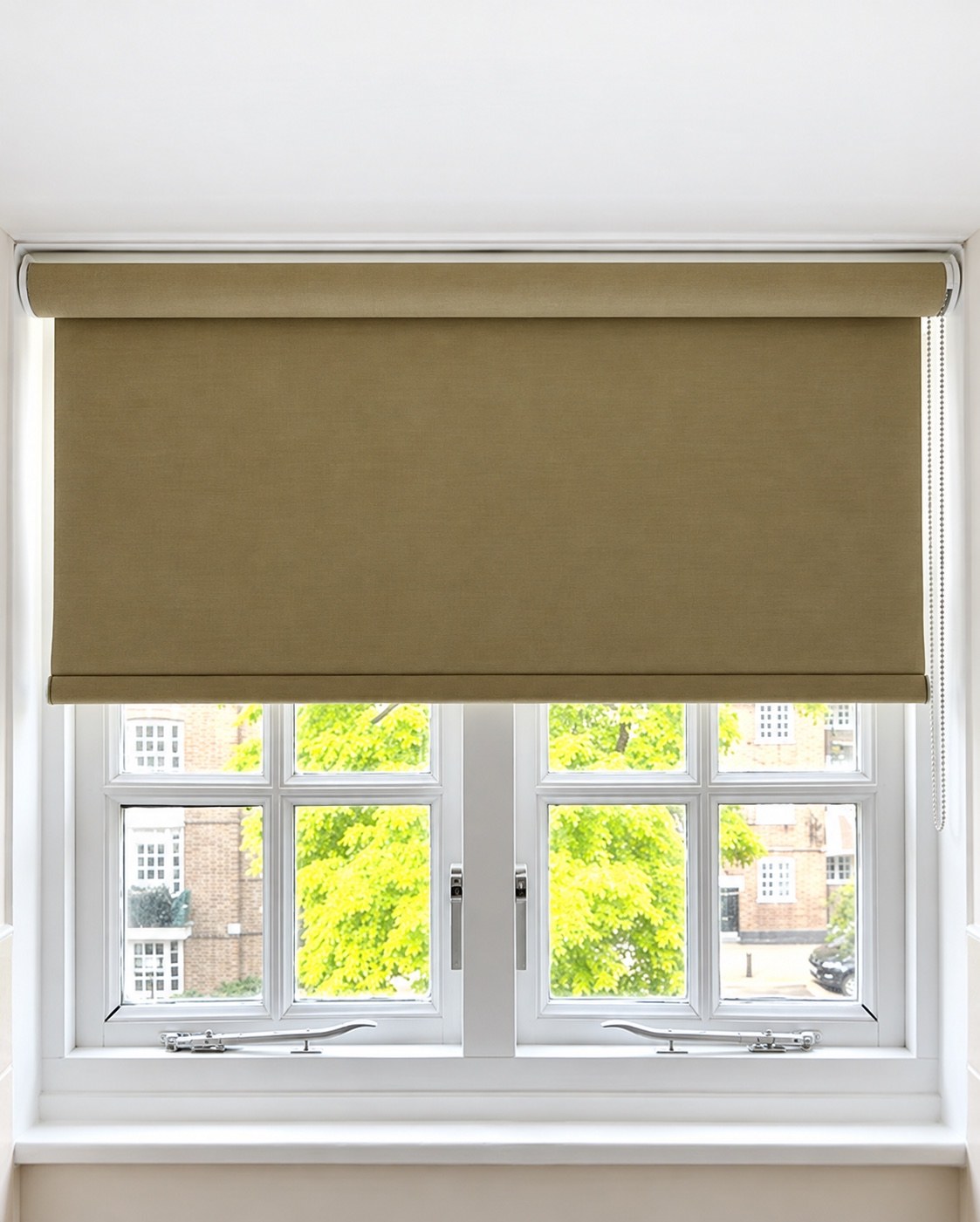 Taupe roller blind half lowered over a white casement window