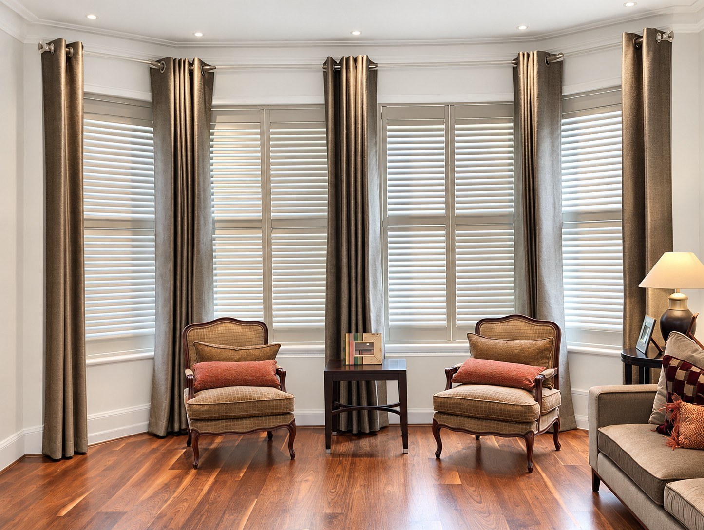 Tier-on-tier shutters in a grand bay window with two armchairs