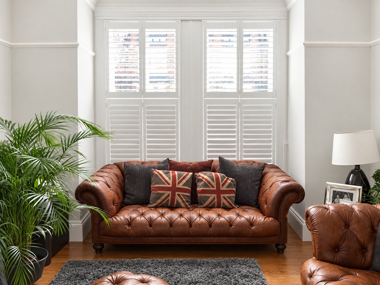 Tier-on-tier shutters above a leather Chesterfield sofa