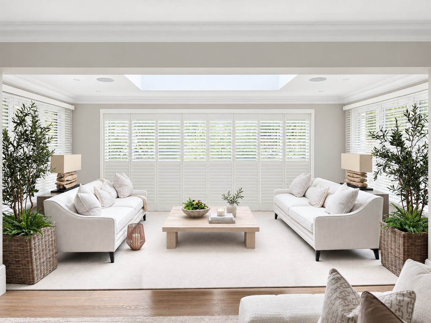 White tracked shutters across a wide opening in a bright living room