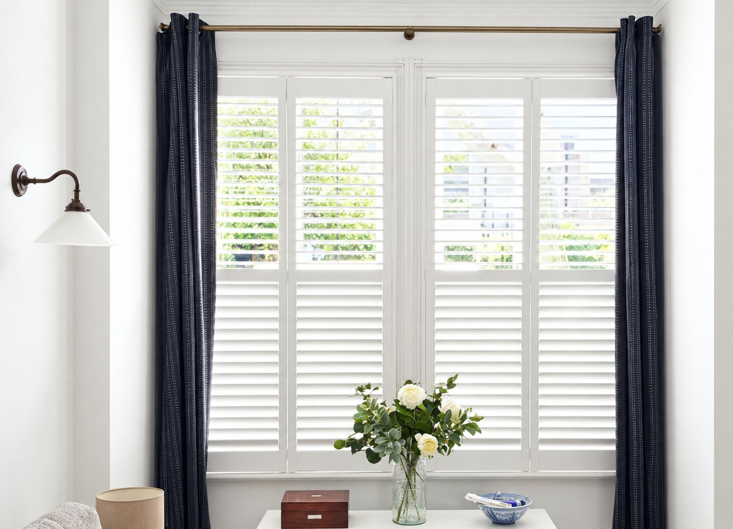 White shutters framed by navy curtains in a living room