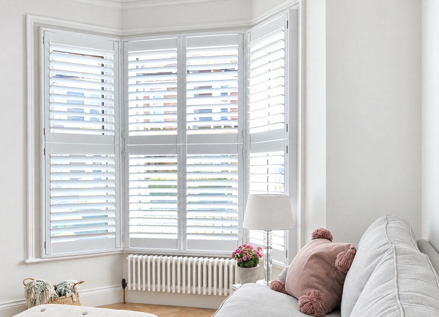 White tier-on-tier shutters in a bay window beside a white sofa