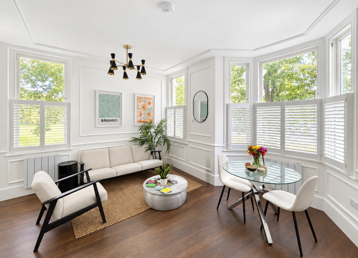 White café-style shutters across the bay and side windows of a bright, open living room