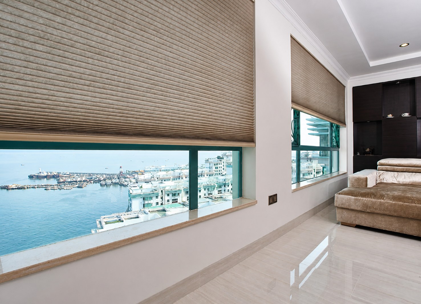 Honeycomb blinds fitted across wide lounge windows overlooking the sea