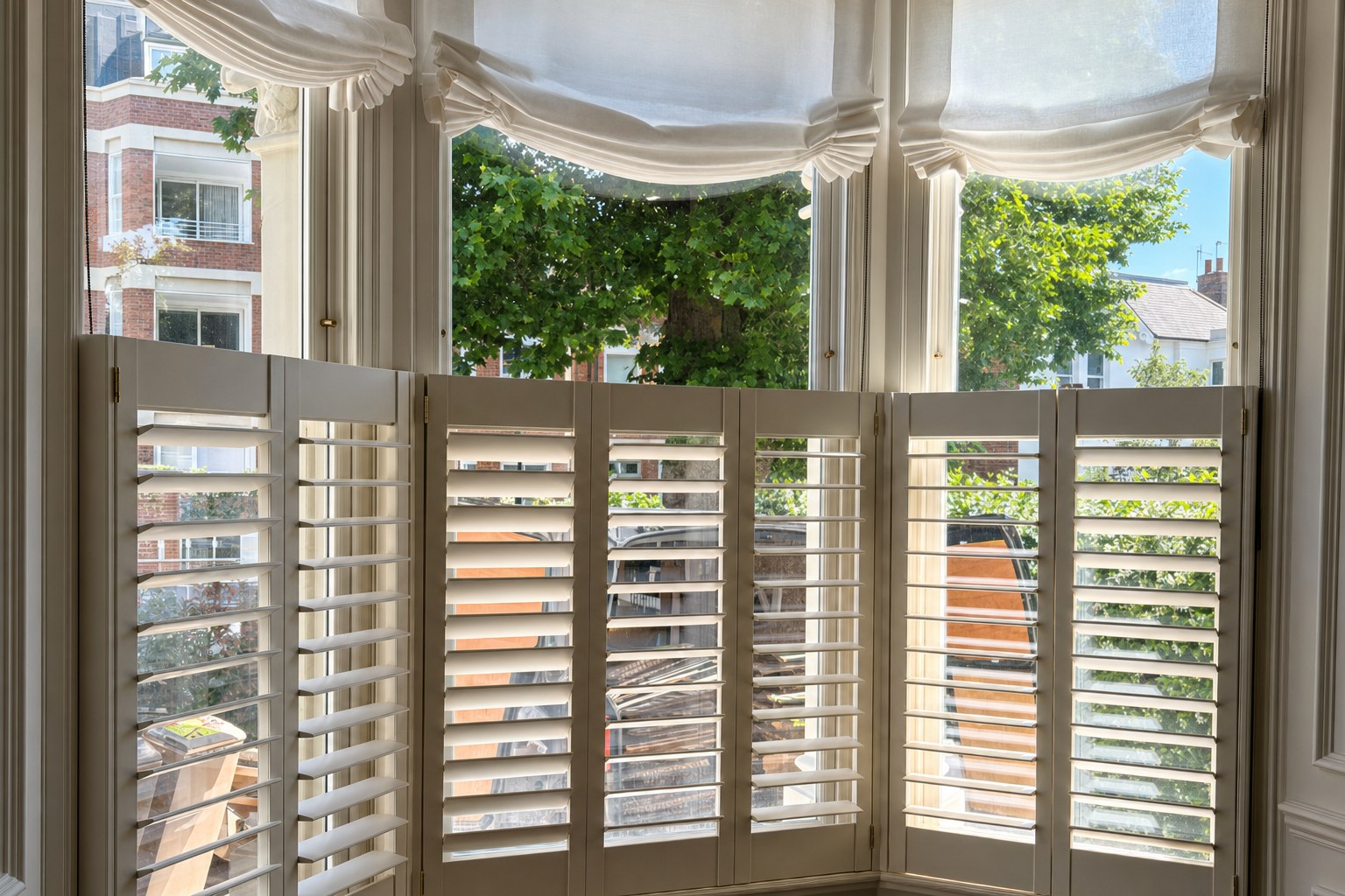 Café style plantation shutters fitted to a Victorian bay window in Ealing