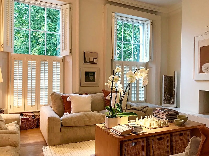 Tier-on-tier wooden shutters framing large sash windows in a Chelsea apartment