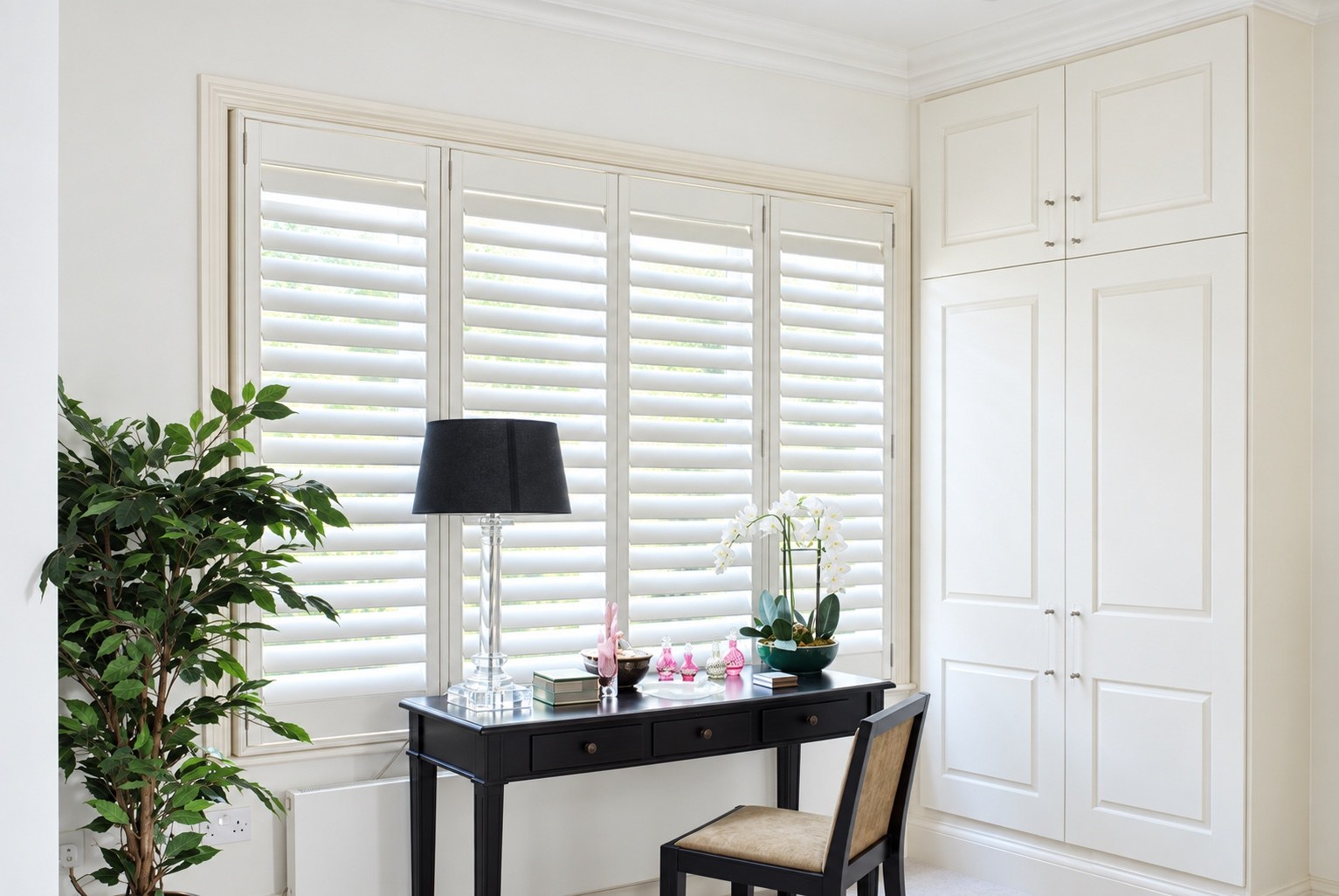 Full height white shutters fitted in a bedroom