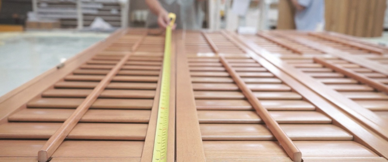 A Shutter Shop specialist measuring shutter panels with a tape measure