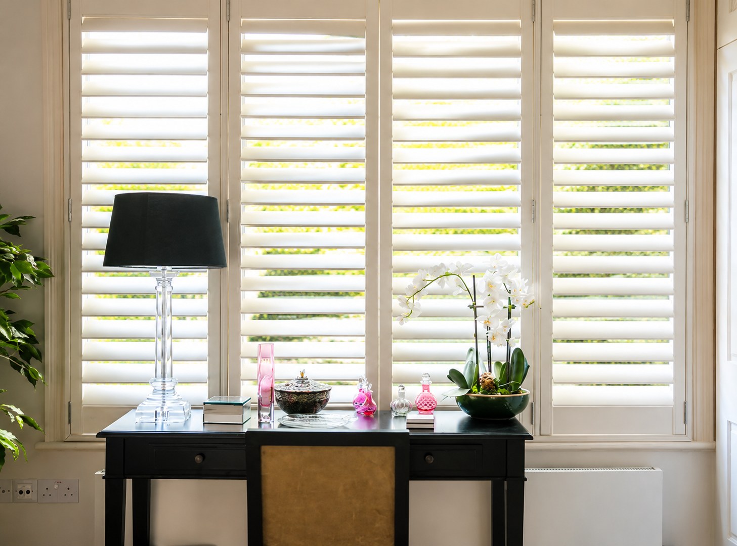 White Café Style Bermuda shutters fitted across a bright home-office window