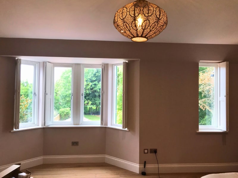 Open solid shutters installed in a bay window in Thames Ditton, Surrey