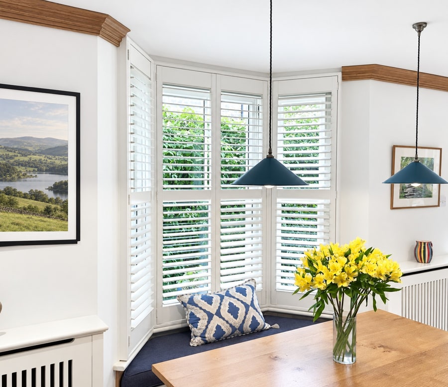 White full-height shutters fitted to a kitchen bay window in Battersea with a window seat