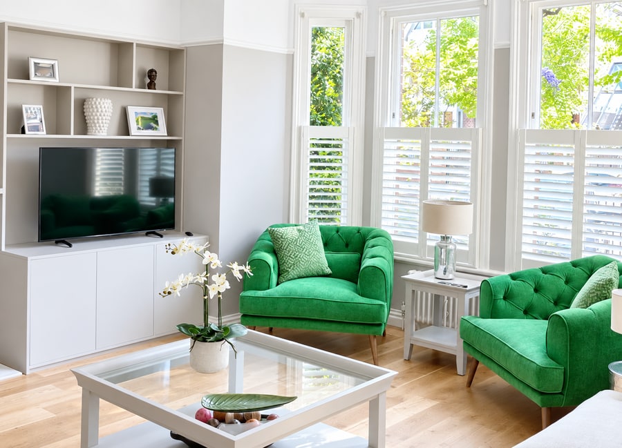 Café style shutters in a living room with green armchairs