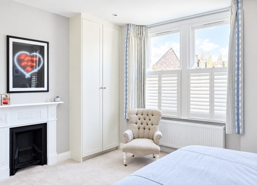 Café style shutters in a bedroom with a fireplace