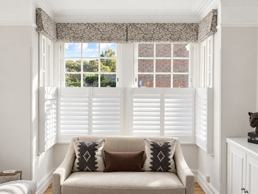 Café style shutters in a bay with a patterned blind
