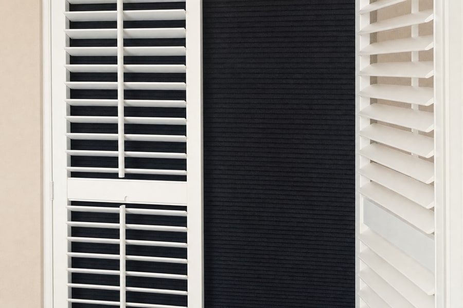 Detail of a room darkening blind behind shutter louvres