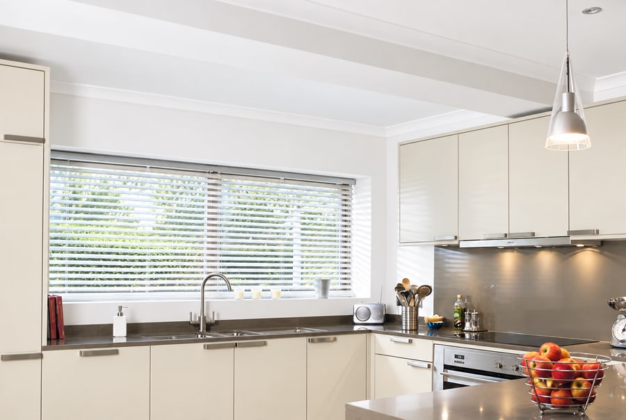 White wooden Venetian blind on a wide kitchen window above the sink
