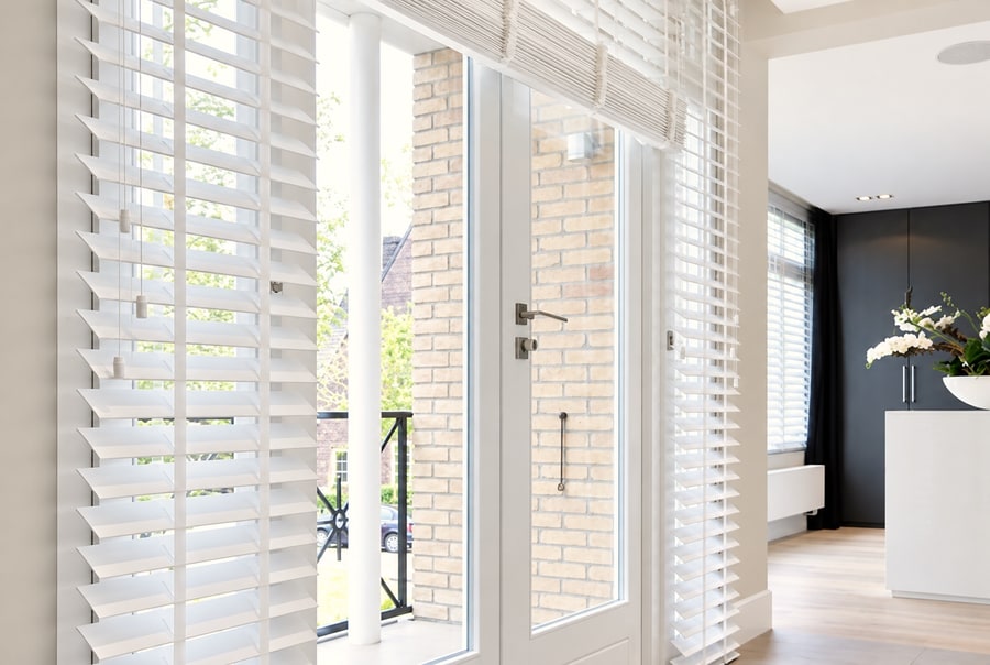White wooden Venetian blinds on tall glazed doors and windows